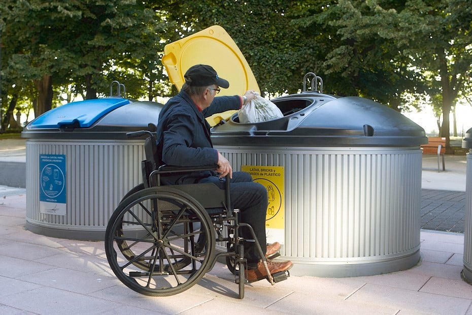 Mies pyörätuolissa lajittelee jätteitä